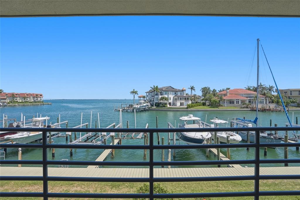 A living room features gray leather furniture, a media console, and sliding doors overlooking water — 363 PINELLAS BAYWAY S UNIT 29, TIERRA VERDE, FL