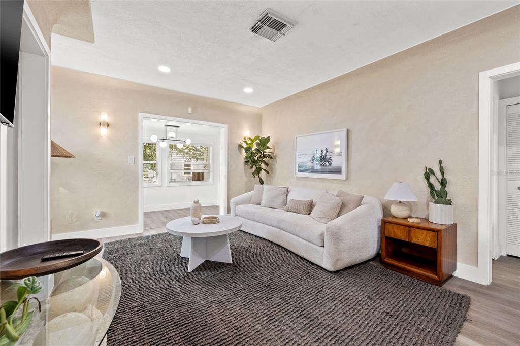 A living room features a wall-mounted television, a glass console table, and a white sofa — 3731 6TH AVENUE N, ST PETERSBURG, FL