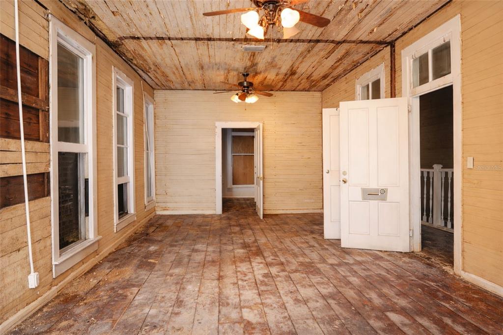 An interior room with wood-plank walls, a weathered ceiling, and exposed wooden floorboards — 528 12TH STREET W, BRADENTON, FL