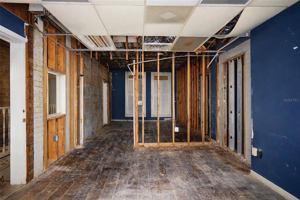 An interior room under renovation with exposed wall studs, a drop ceiling, and wood flooring — 528 12TH STREET W, BRADENTON, FL