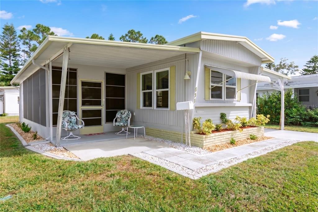 A single-story manufactured home with a screened-in porch, light siding, and a small front garden — 1800 ENGLEWOOD ROAD UNIT 137, ENGLEWOOD, FL