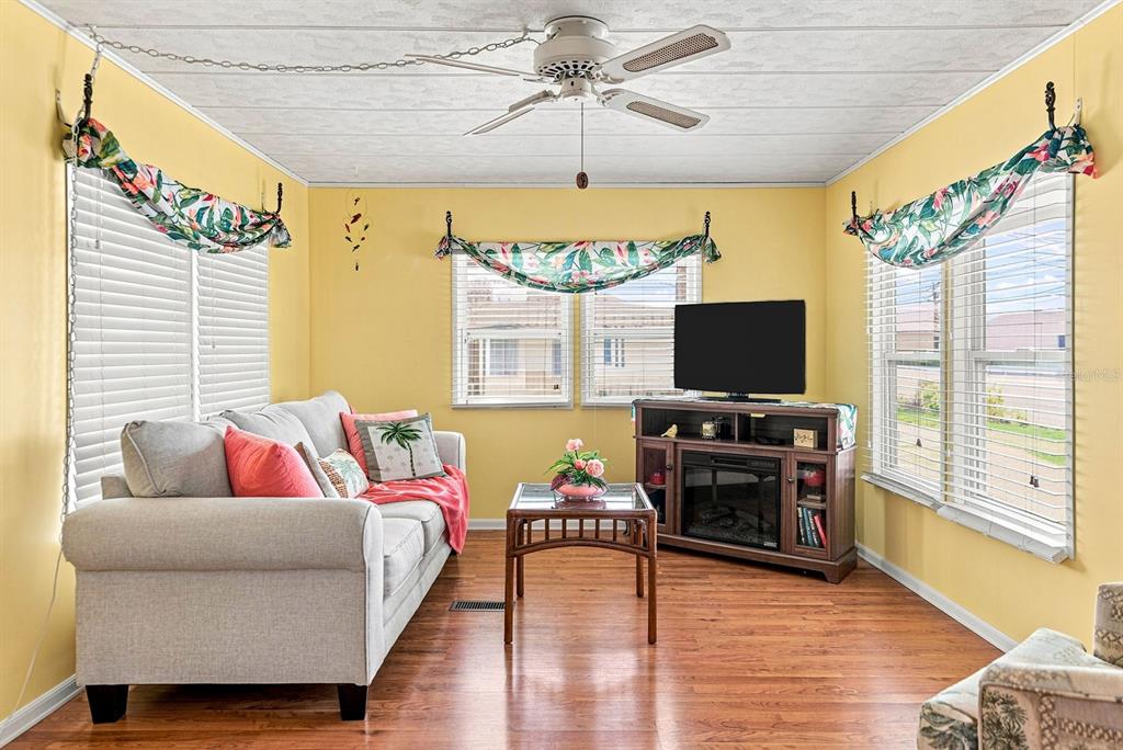 A living room with yellow walls, a light gray sofa, and a wooden media console — 1800 ENGLEWOOD ROAD UNIT 137, ENGLEWOOD, FL