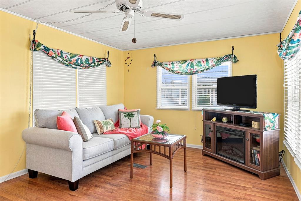 A living room with yellow walls, a gray sofa, a coffee table, and a television console — 1800 ENGLEWOOD ROAD UNIT 137, ENGLEWOOD, FL