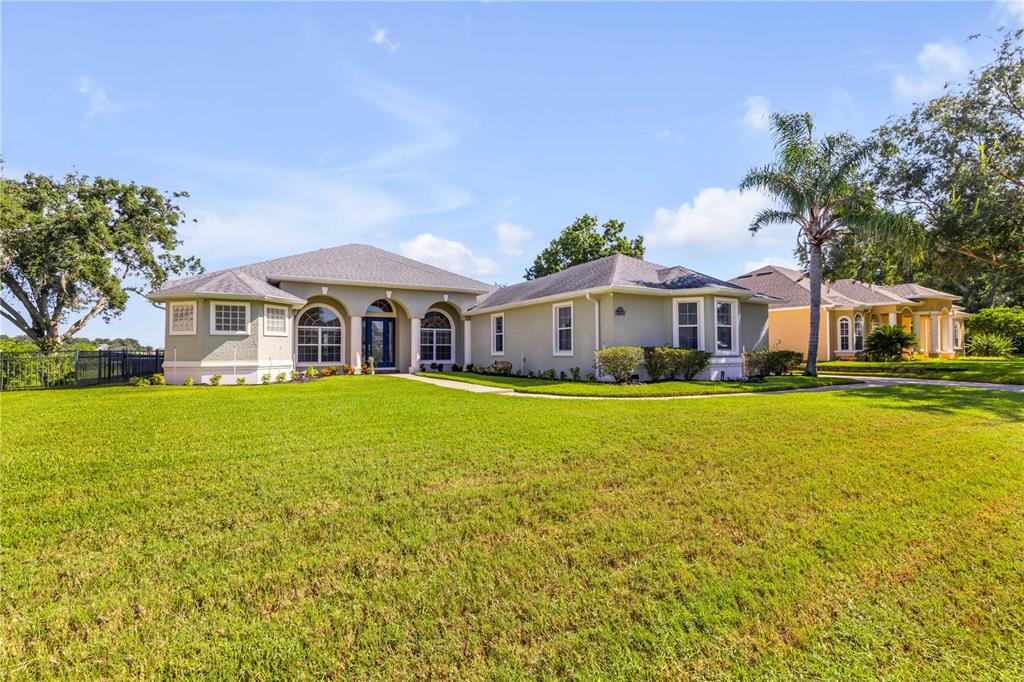 A single-story suburban house with a light-colored stucco exterior and a large front lawn — 10749 ASTATULA LANE, CLERMONT, FL