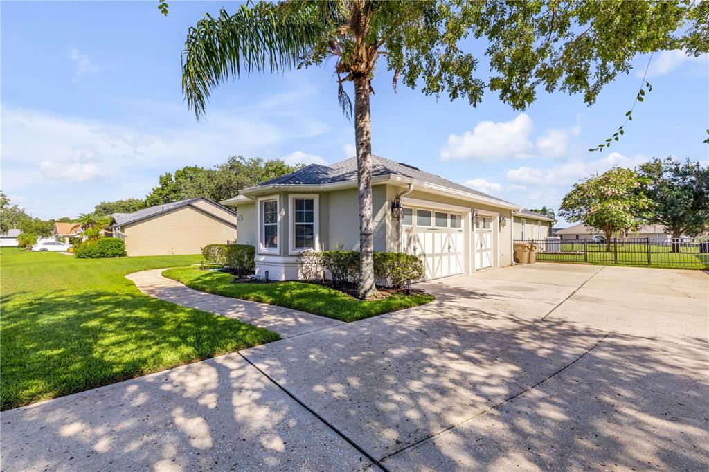 A beige house with a two-car garage and a palm tree in the front yard — 10749 ASTATULA LANE, CLERMONT, FL