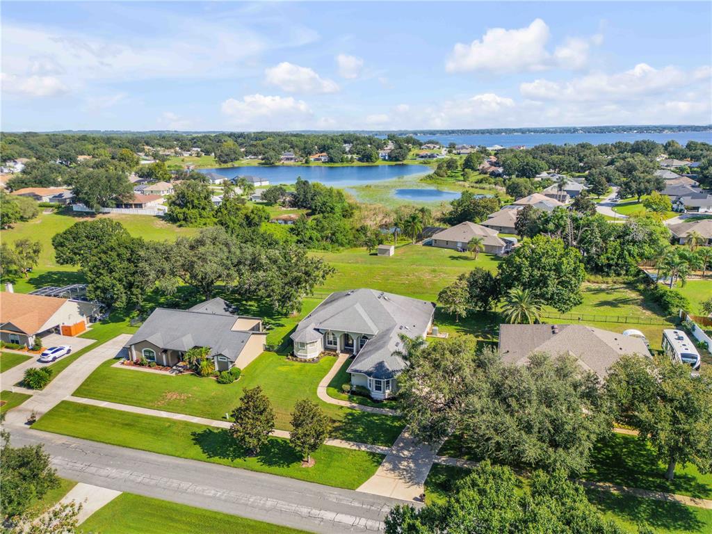 An aerial view shows suburban houses with large yards near a lake and trees — 10749 ASTATULA LANE, CLERMONT, FL