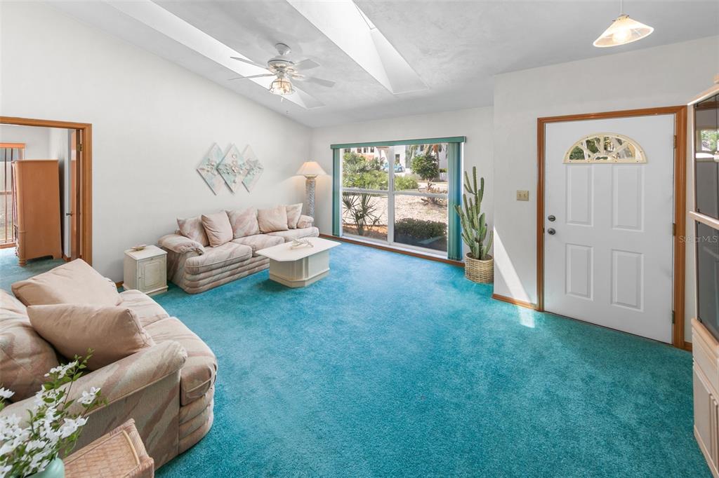 A living room features teal carpeting, vaulted ceilings with a skylight, and a white front door — 4715 S PENINSULA DRIVE, PONCE INLET, FL