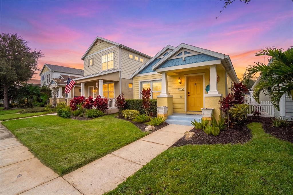 A yellow house with a front porch and a walkway sits next to another home — 4718 FOREST CREEK TRAIL, PARRISH, FL