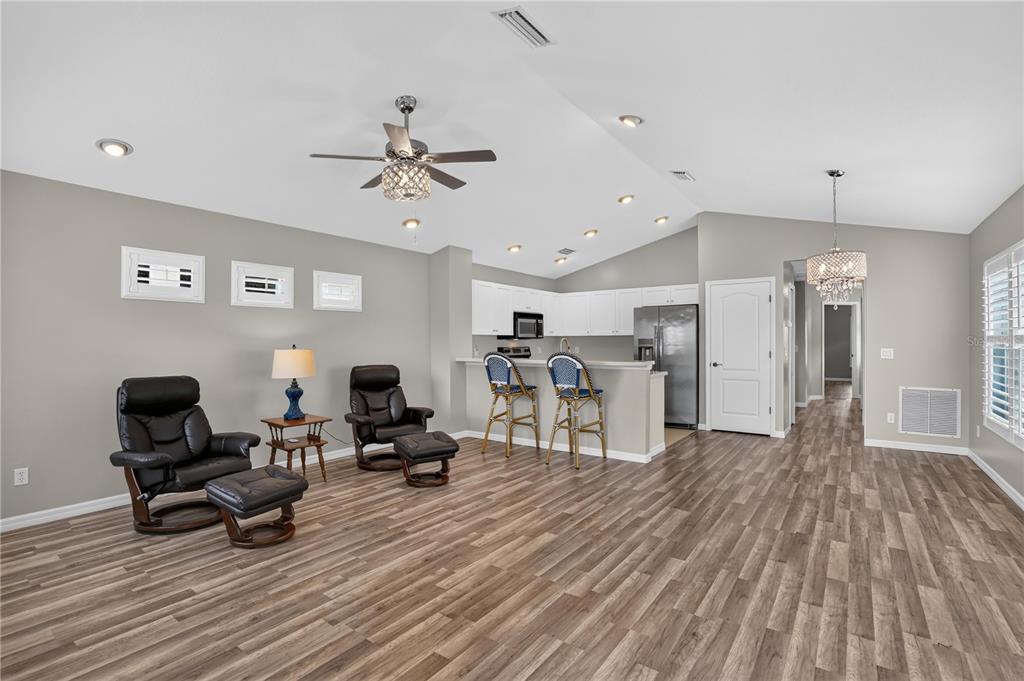 A living room with wood-look flooring, two leather recliners, and an open kitchen with barstools — 4718 FOREST CREEK TRAIL, PARRISH, FL