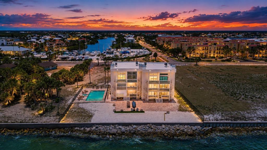 An aerial view shows a modern three-story house with a pool beside a waterfront seawall — 6504 SURFSIDE BOULEVARD UNIT 8, APOLLO BEACH, FL
