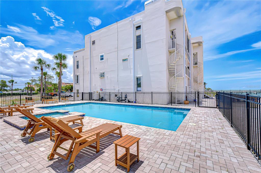 A swimming pool with lounge chairs sits in front of a multi-story white building — 6504 SURFSIDE BOULEVARD UNIT 8, APOLLO BEACH, FL