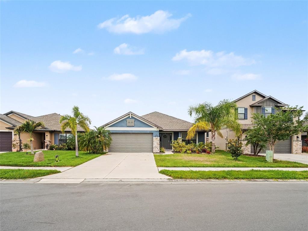 A single-story house with a blue facade, stone accents, and a two-car garage — 16137 61ST LANE E, PARRISH, FL