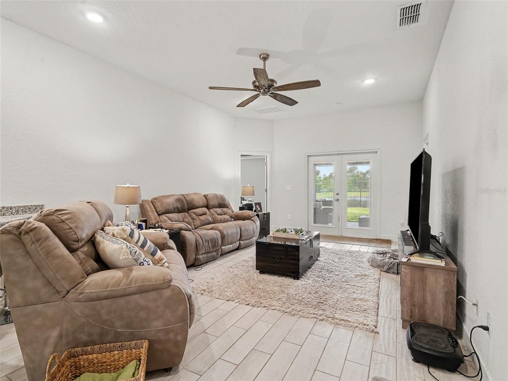 A living room features two brown reclining sofas, a coffee table, and glass patio doors — 16137 61ST LANE E, PARRISH, FL