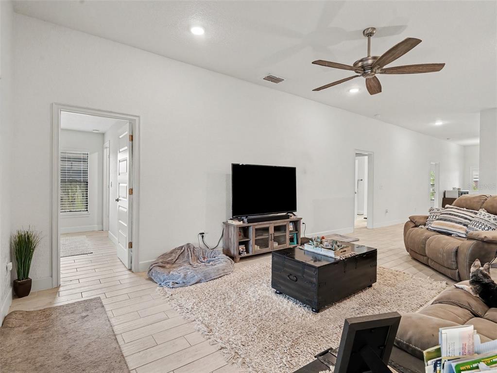 A living room features white walls, tile flooring, a ceiling fan, and a television console — 16137 61ST LANE E, PARRISH, FL