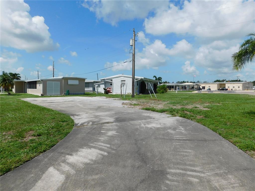 A concrete driveway leads to a vacant lot with a mobile home in the background — 1205 43RD AVENUE DRIVE E, ELLENTON, FL