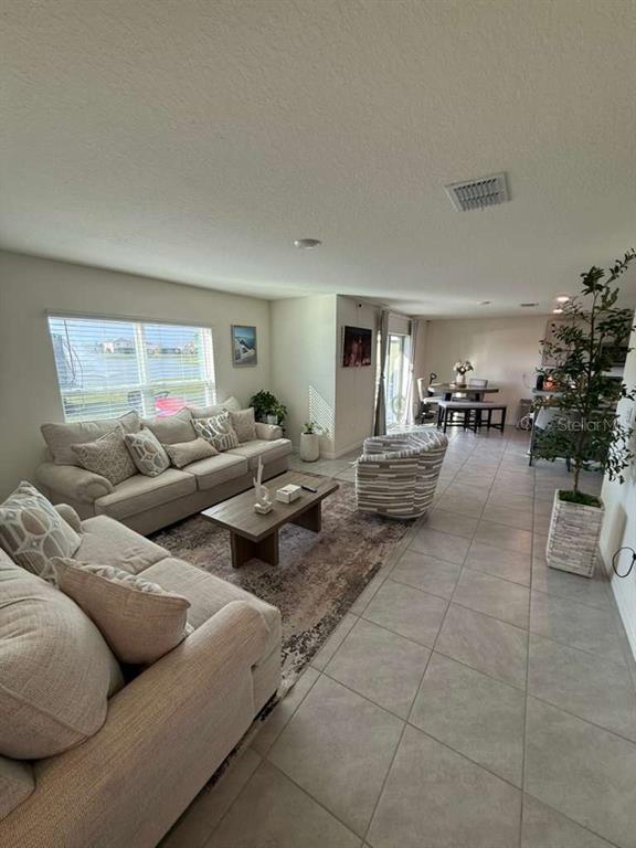 A living room with tile floors, a beige sofa, and a dining area in the background — 10662 CHIPPEWA DRIVE, PARRISH, FL