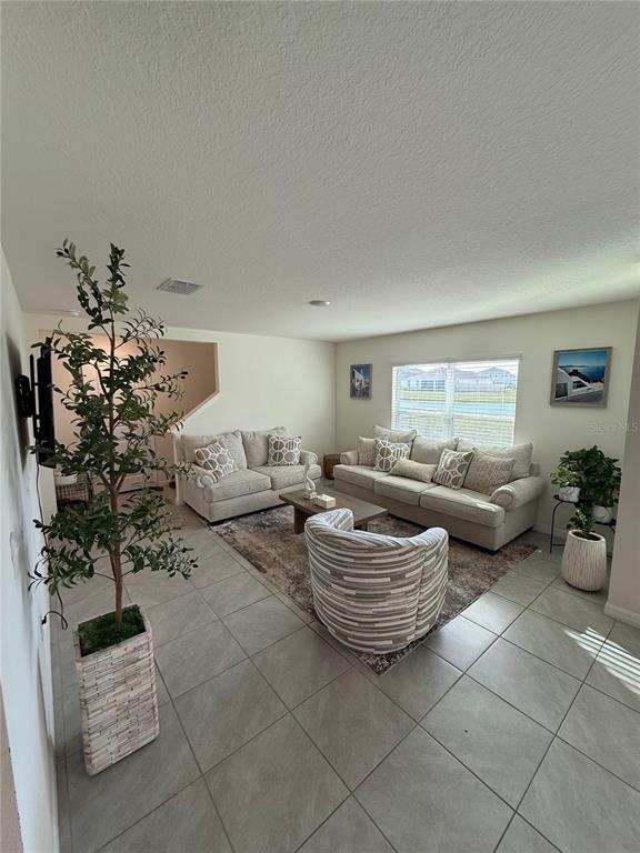 A living room features light-colored sofas, a patterned armchair, and tile flooring — 10662 CHIPPEWA DRIVE, PARRISH, FL