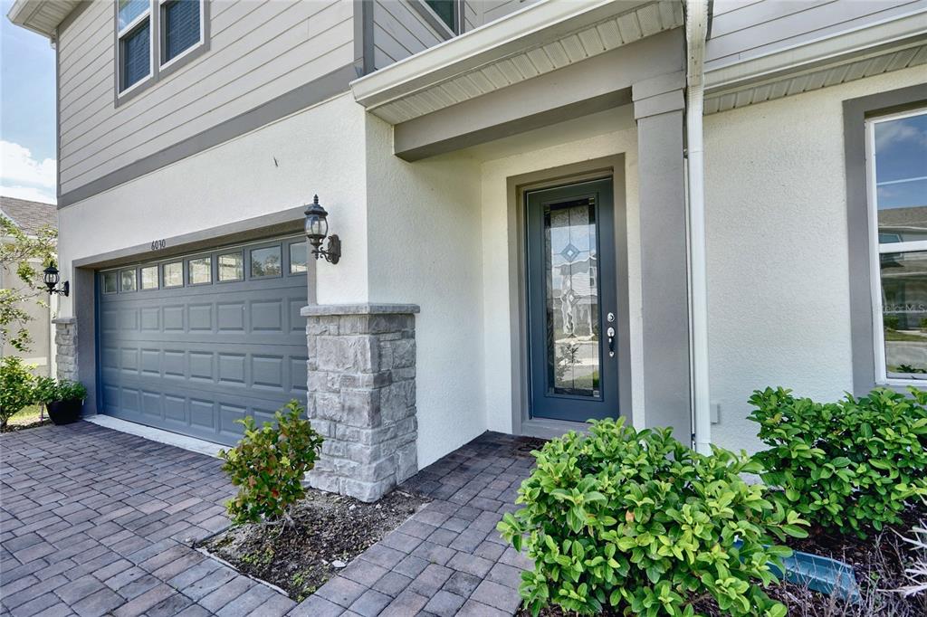 The exterior of a house features a gray garage door, stone accents, and a front entrance — 6030 ARBOR WATCH LOOP, ORLANDO, FL