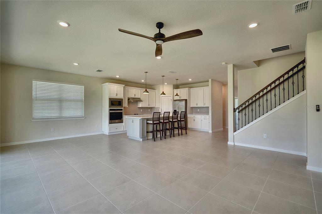 An open-concept kitchen with white cabinetry, a central island with seating, and a staircase nearby — 6030 ARBOR WATCH LOOP, ORLANDO, FL