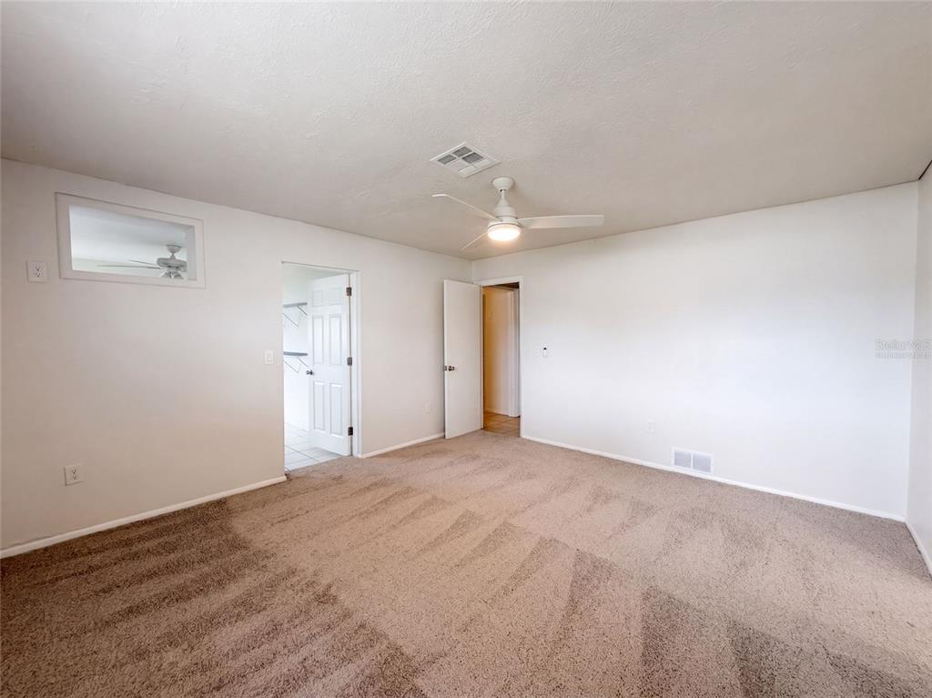 An empty bedroom features beige carpeting, white walls, a ceiling fan, and two doorways — 124 SAN BENITO AVENUE, NORTH PORT, FL