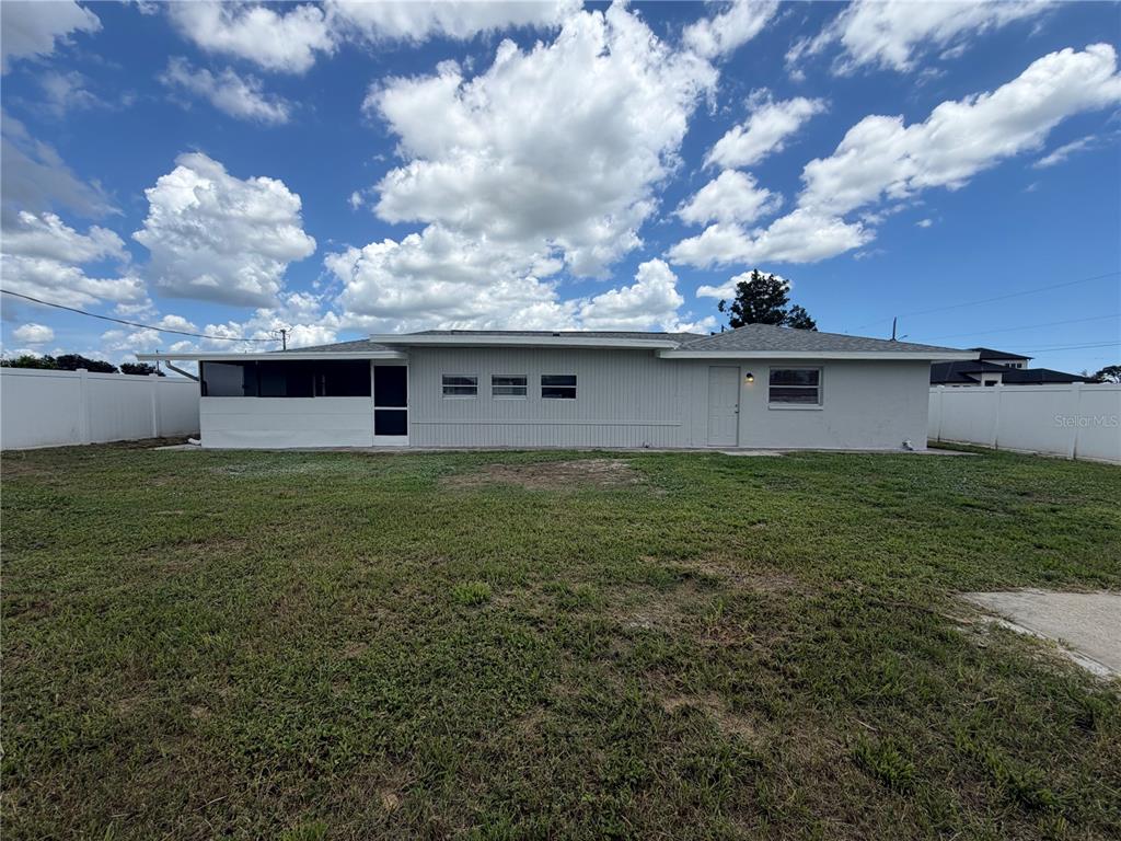 A single-story house with a screened-in porch and white siding sits in a large yard — 124 SAN BENITO AVENUE, NORTH PORT, FL