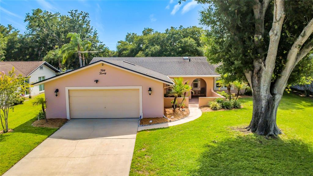 An aerial view of a single-story house with a garage, pool enclosure, and large trees — 5020 THE OAKS CIRCLE, ORLANDO, FL