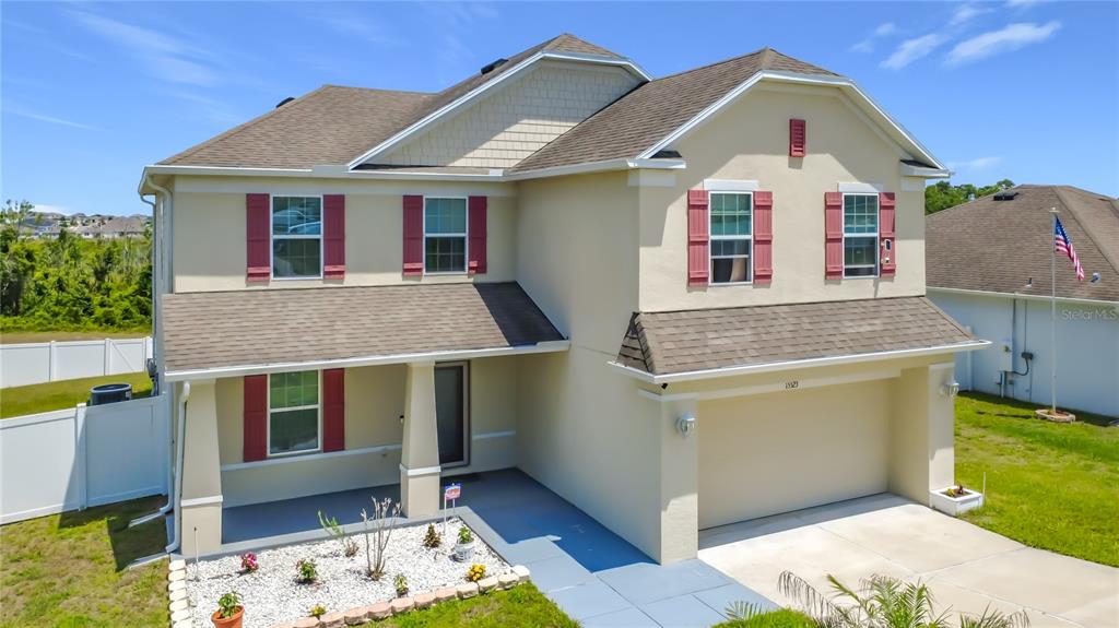 A two-story suburban house with a beige stucco exterior, red shutters, and a two-car garage — 15523 GEMINI DRIVE, MASCOTTE, FL