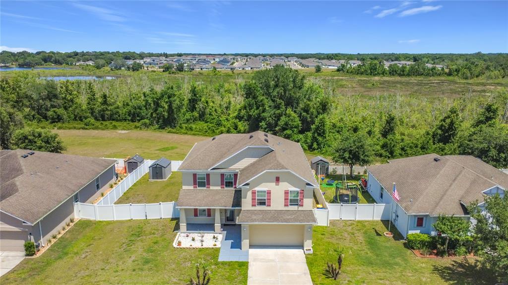 An aerial view shows a two-story suburban house with a tan exterior and white fencing — 15523 GEMINI DRIVE, MASCOTTE, FL