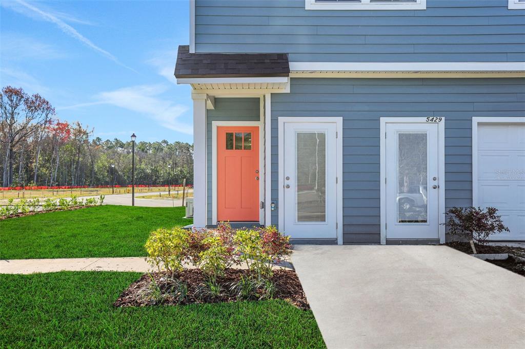 A blue house exterior features a coral front door, two glass-paneled doors, and a driveway — 9174 TENDER LANE, JACKSONVILLE, FL