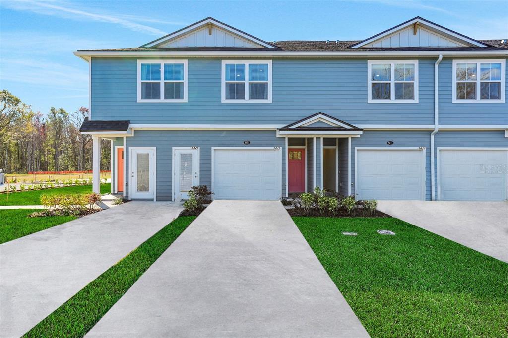 A blue two-story townhouse exterior features multiple garage doors and a small front lawn — 9174 TENDER LANE, JACKSONVILLE, FL