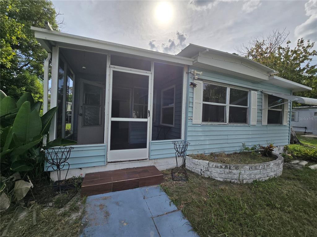 A light blue house features a screened-in porch, a tiled step, and a stone planter — 5414 TAYLOR AVENUE, PORT ORANGE, FL