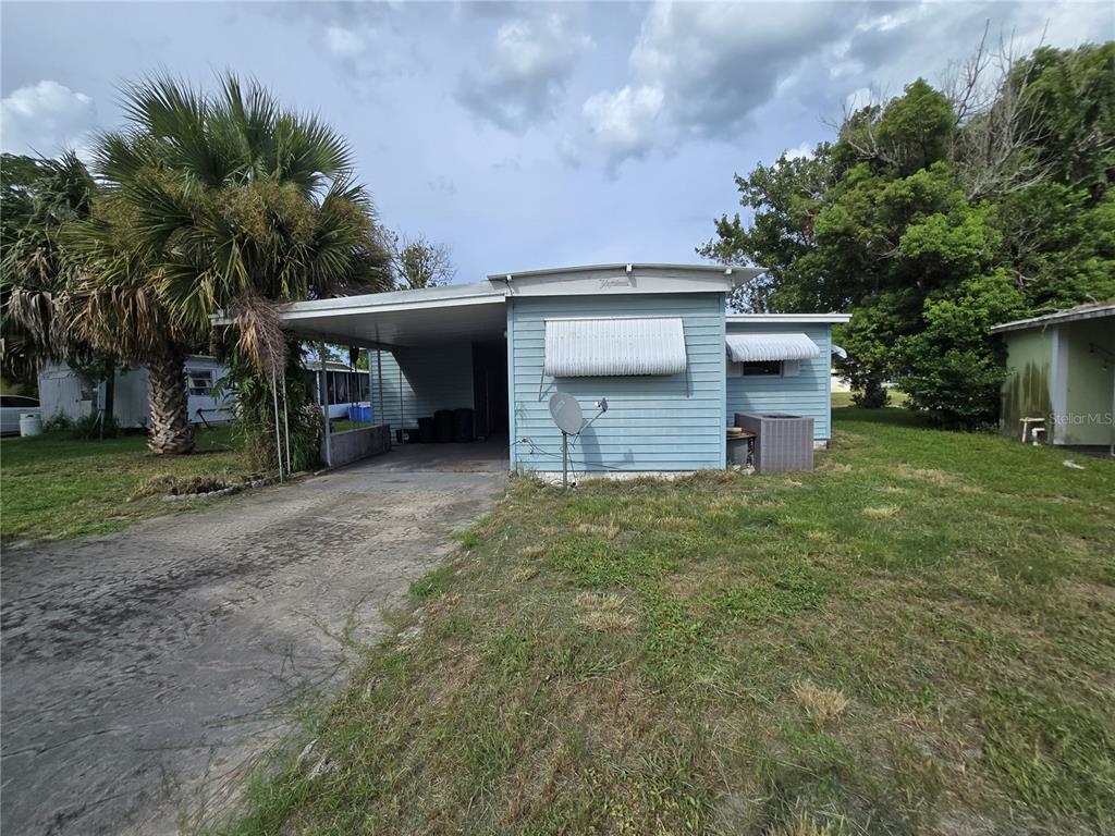 A light blue mobile home features a carport and a concrete driveway on a grassy lot — 5414 TAYLOR AVENUE, PORT ORANGE, FL