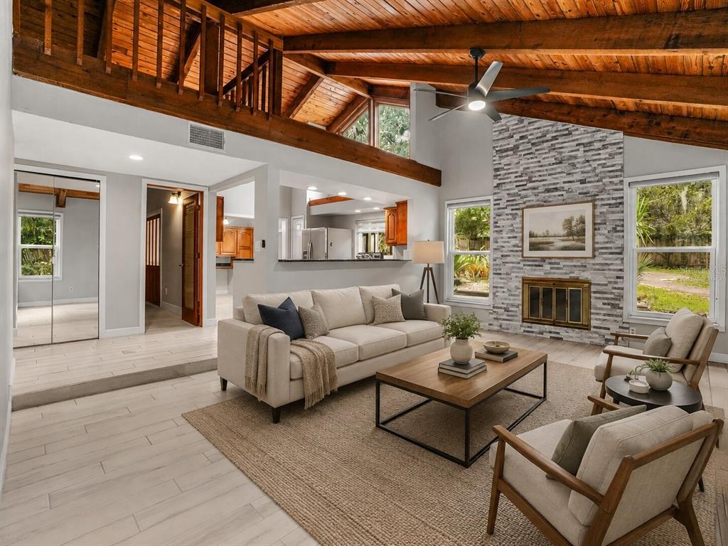 A living room with a vaulted wood-beam ceiling, stone fireplace, and light-colored tile flooring — 280 HUNTERS POINT TRAIL, LONGWOOD, FL
