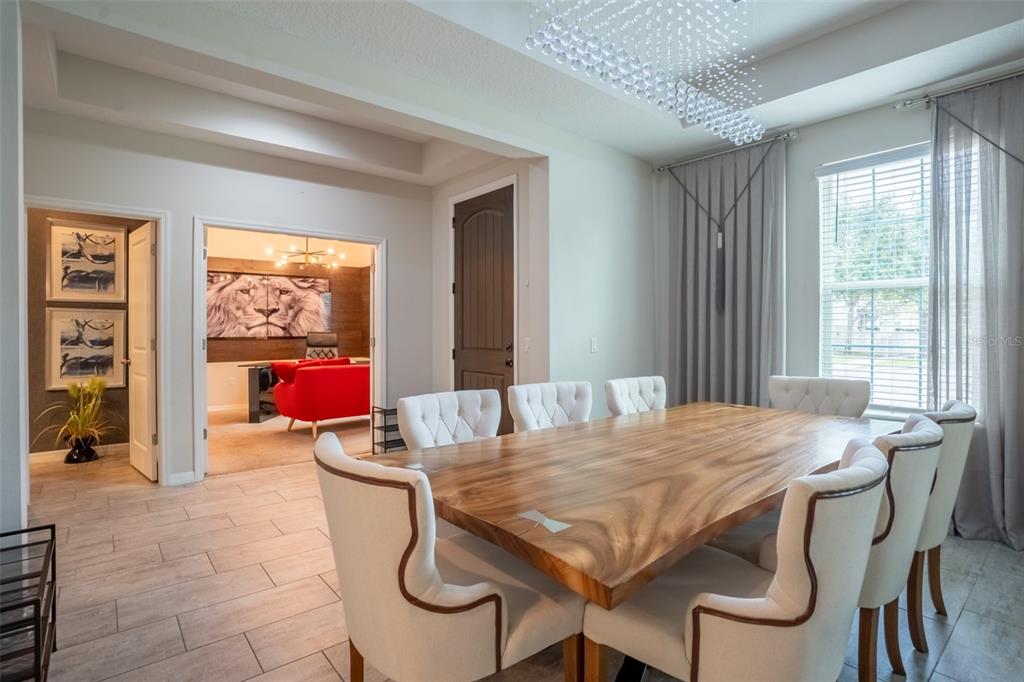 A dining room features a large wooden table, tufted chairs, and a view into an office — 8304 LOOKOUT POINTE DRIVE, WINDERMERE, FL