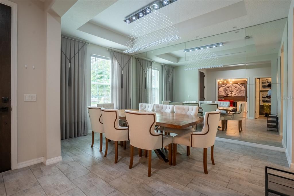 A dining room features a wooden table, upholstered chairs, a crystal chandelier, and mirrored walls — 8304 LOOKOUT POINTE DRIVE, WINDERMERE, FL
