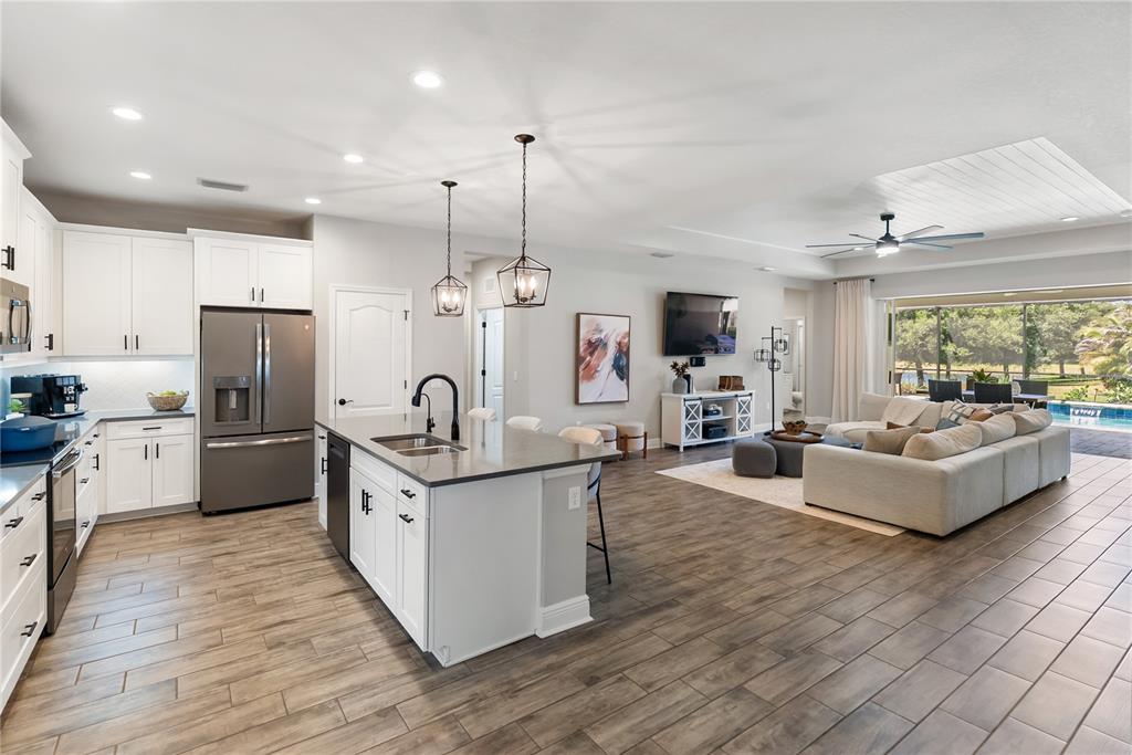 An open-concept kitchen and living area features white cabinetry, a kitchen island, and tile flooring — 1215 THORNBURY DRIVE, PARRISH, FL