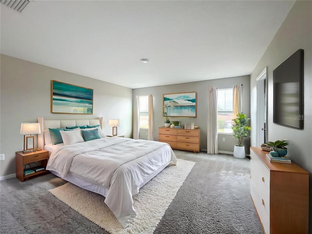 A bedroom features a white bed, two wooden dressers, gray carpeting, and two windows — 1404 AXEL CIRCLE, WINTER HAVEN, FL
