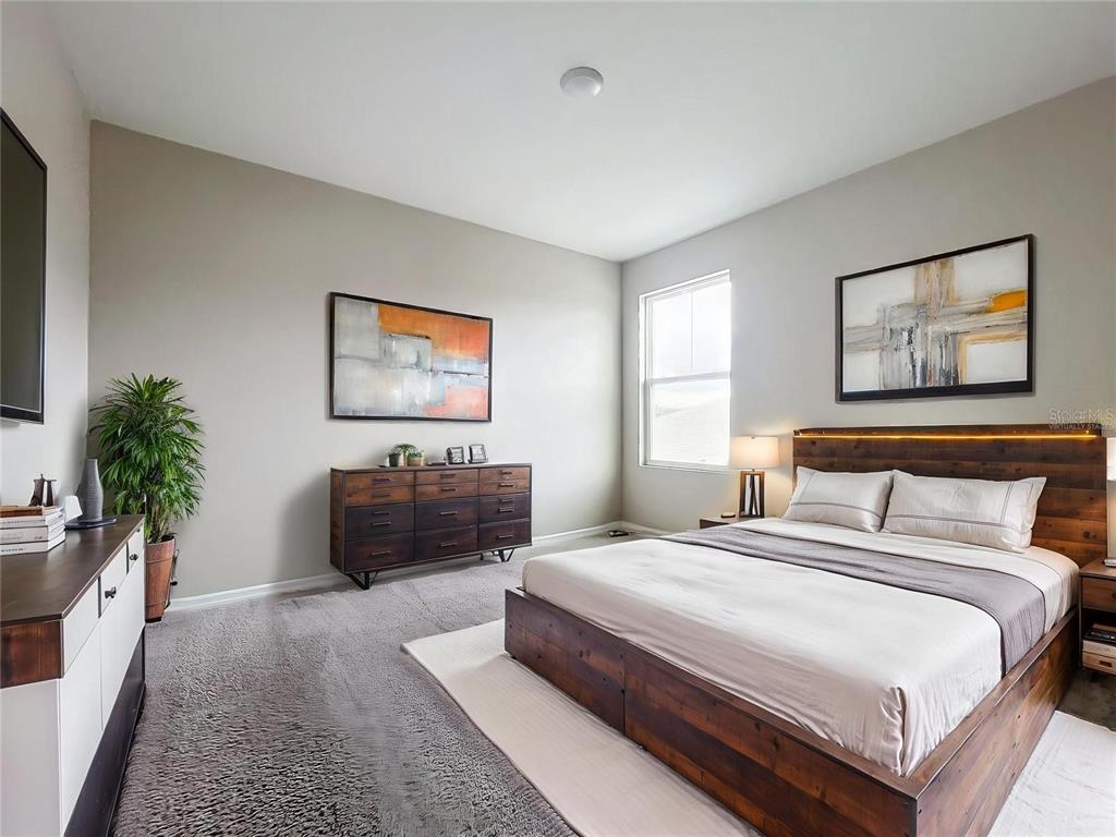 A bedroom features a wooden bed frame, a matching dresser, and gray carpeting — 1404 AXEL CIRCLE, WINTER HAVEN, FL