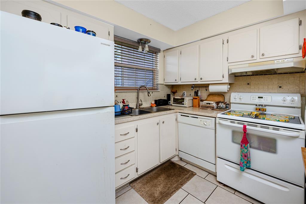 A living room features a blue leather sofa, a red patterned rug, and sliding glass doors — 3435 41ST TERRACE S UNIT 198, ST PETERSBURG, FL
