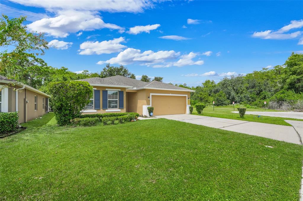 A single-story tan house with a two-car garage and a green lawn — 221 DAIGLEDOG STREET, ST CLOUD, FL