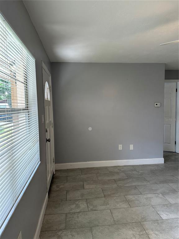 A living room with gray walls, tile flooring, a ceiling fan, and a window with blinds — 473 93RD AVENUE N, ST PETERSBURG, FL