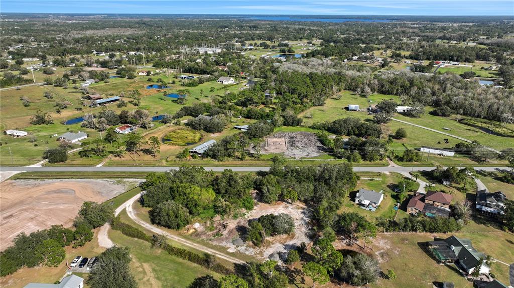 An aerial view shows a rural landscape with scattered houses, trees, ponds, and a dirt road — CANOE CREEK ROAD, ST CLOUD, FL