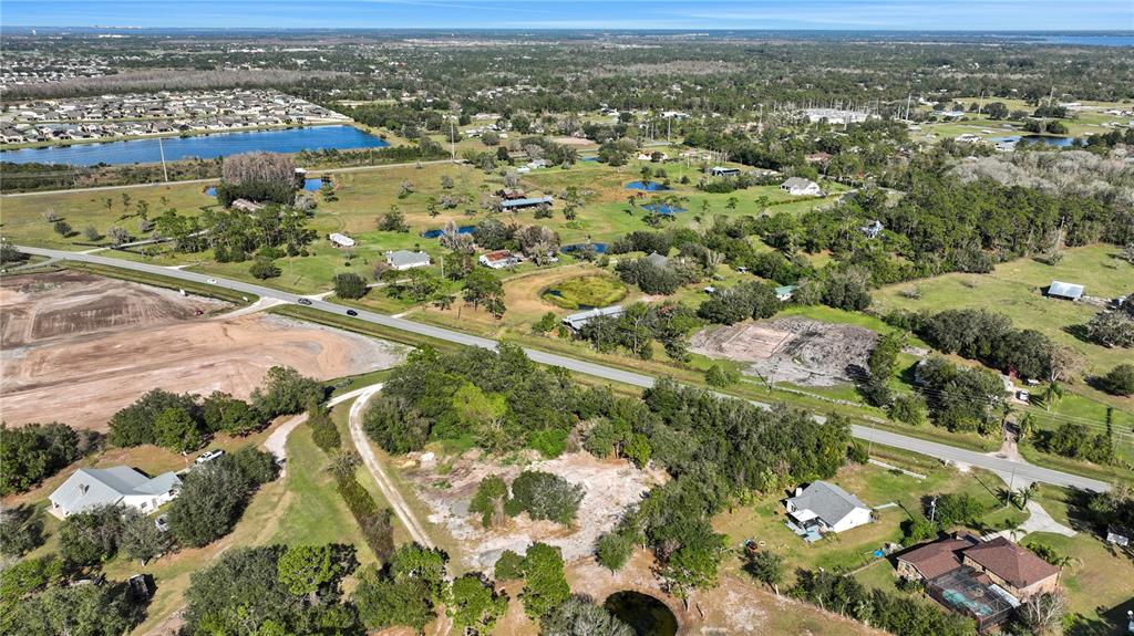 An aerial view shows a rural landscape with scattered houses, ponds, and a paved road — CANOE CREEK ROAD, ST CLOUD, FL