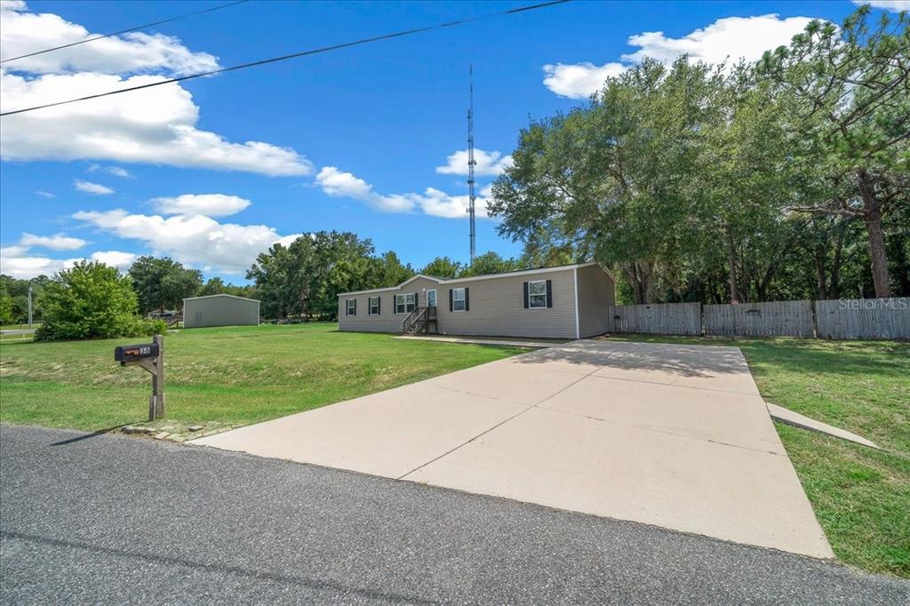 A single-story manufactured home with a concrete driveway and a wooden fence in the yard — 38 SE 70TH CIRCLE, OCALA, FL