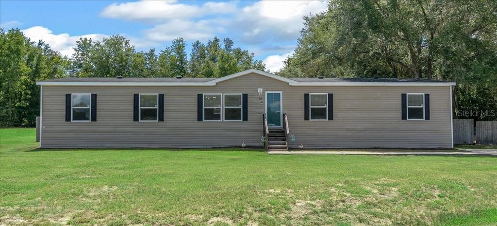 A single-story manufactured home with tan siding, a dark roof, and a front entrance — 38 SE 70TH CIRCLE, OCALA, FL