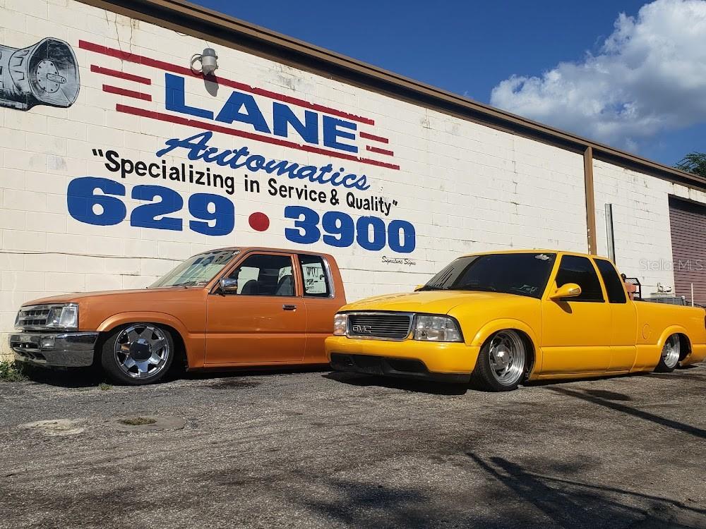 Two lowered pickup trucks are parked in front of a building with painted signage — 212 NW 20TH STREET, OCALA, FL
