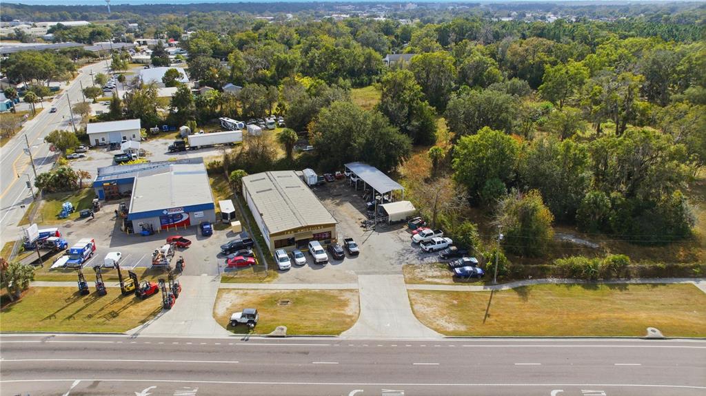 An aerial view shows two commercial buildings with parking lots situated next to wooded land — 212 NW 20TH STREET, OCALA, FL