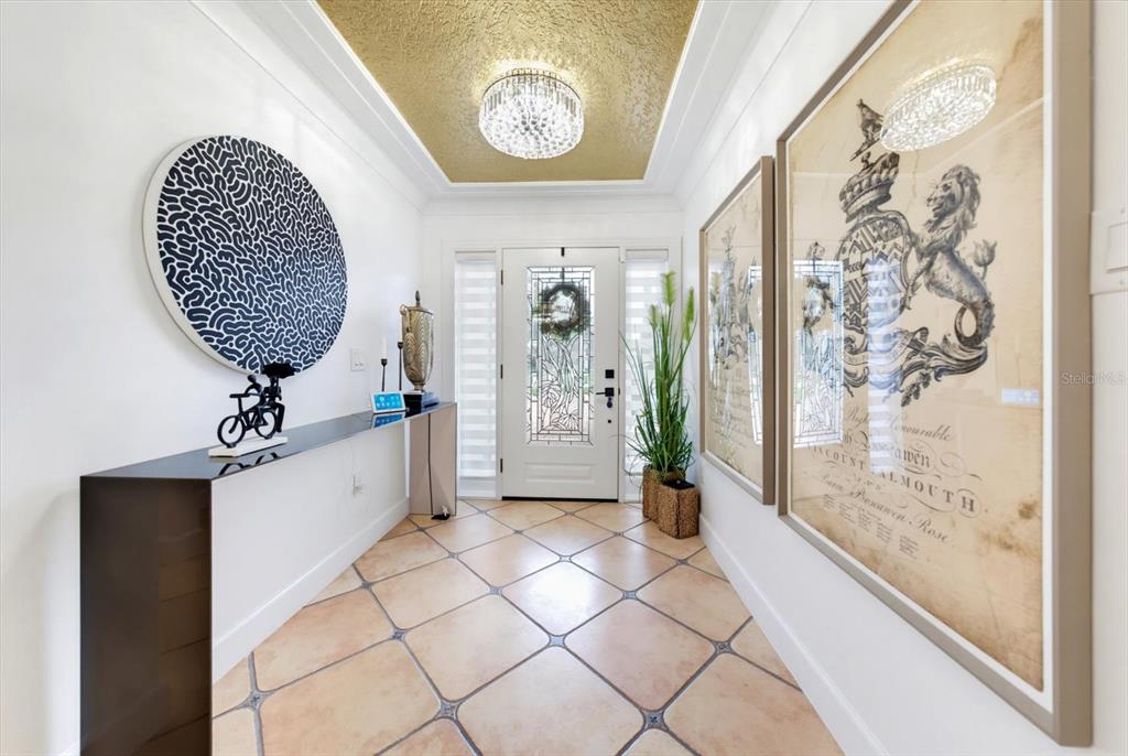 A bright entryway features a gold-painted ceiling, tiled floors, a console table, and framed artwork — 407 HARBOR VIEW LANE, LARGO, FL