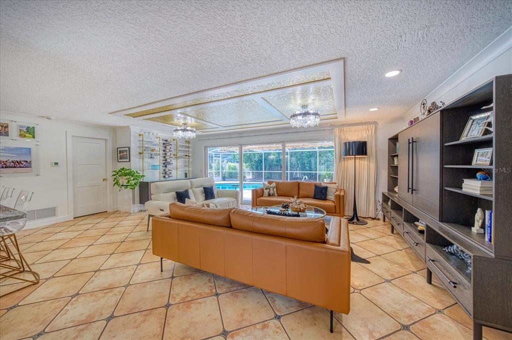 A living room features tan leather sofas, tile flooring, and a gold-accented recessed ceiling — 407 HARBOR VIEW LANE, LARGO, FL