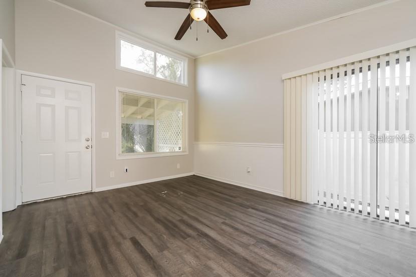 An empty room features wood-look flooring, a ceiling fan, large windows, and vertical blinds — 559 MARTIN PLACE BOULEVARD, APOPKA, FL
